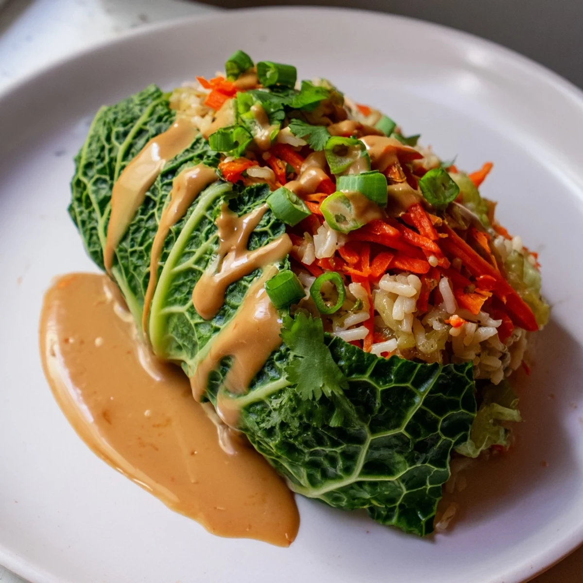 A close-up shot of vegetarian Savoy Cabbage Rolls with rich Thai peanut sauce, a delicious main dish.