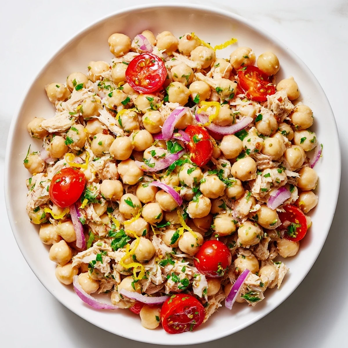 A vibrant bowl of Dense Chickpea and Tuna Salad with fresh herbs and tomatoes.