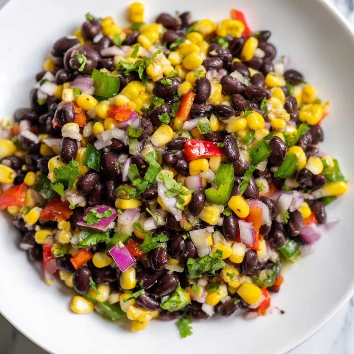 A vibrant bowl of Cowboy Caviar Salad: colorful, chopped vegetables tossed in zesty lime dressing.