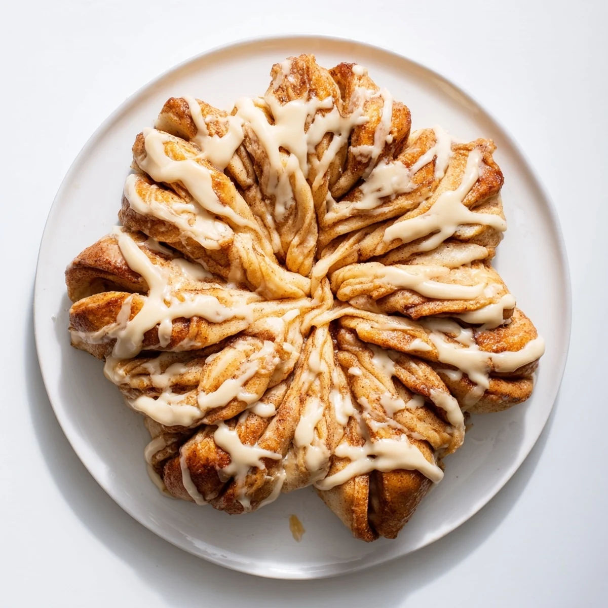 Golden brown Cinnamon Roll Pull-Apart Snowflake, drizzled with vanilla icing and ready to be shared and enjoyed.