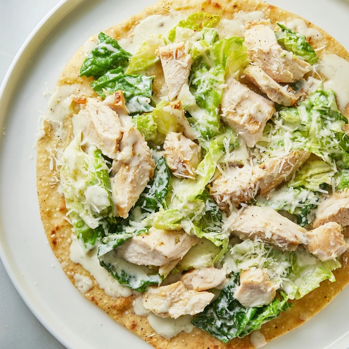 Pizzafusion aus flachem Brot, Hähnchenbruststreifen, frischem Salat und Parmesan – frisch aus dem Ofen.