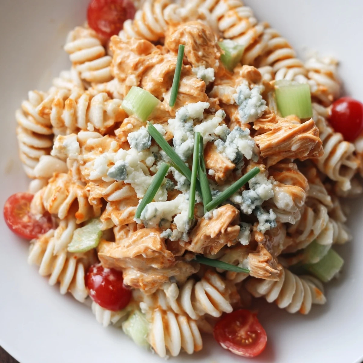 Ein farbenfrohes Bild der Buffalo Chicken Pasta Salad, angerichtet mit Scheiben von Rotpaprika und Stücken von gekochtem Hähnchen.