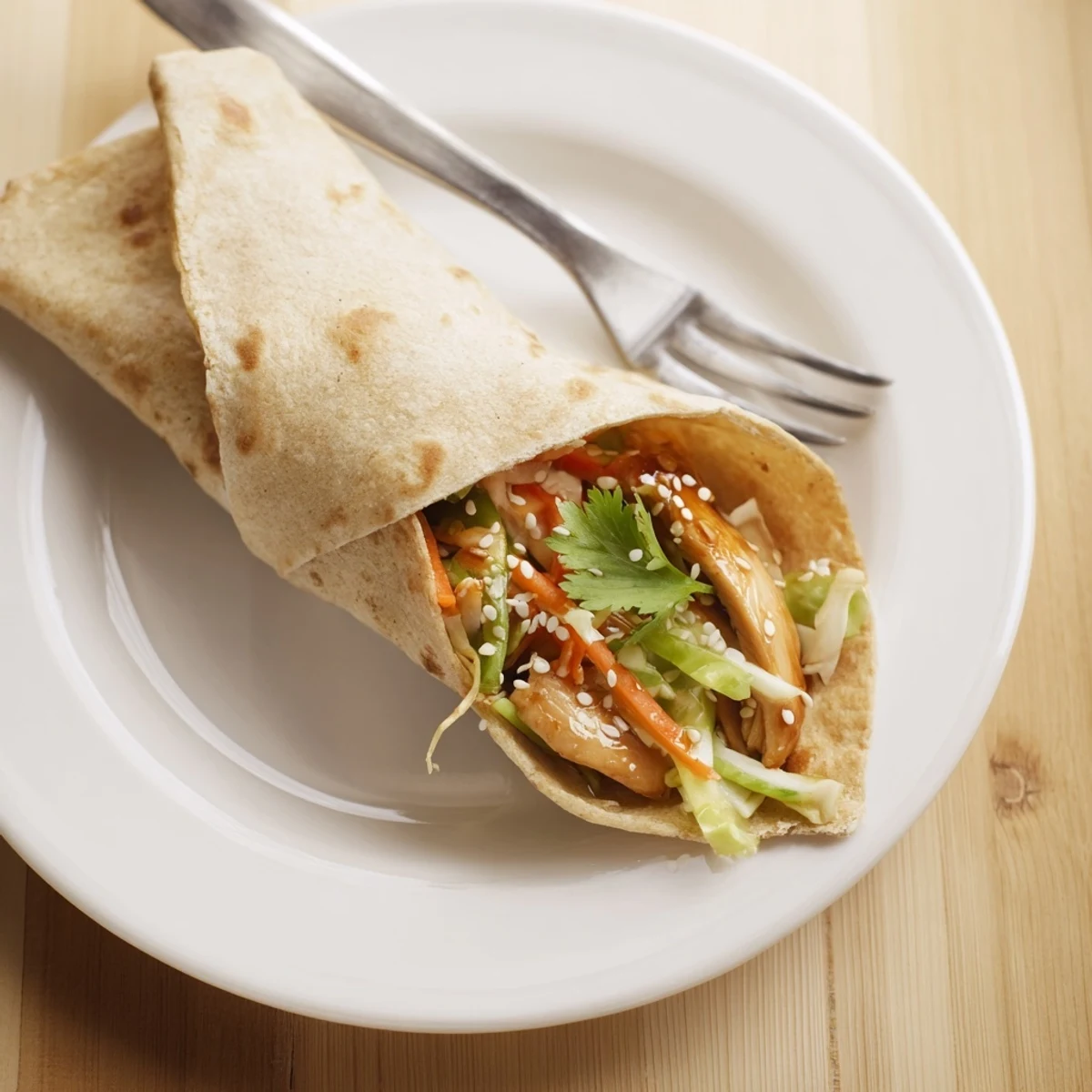 Zarte Hühnchenstreifen in Teriyaki-Sauce, gewickelt in Weizentortillas mit knackigem Kohl und Möhren.