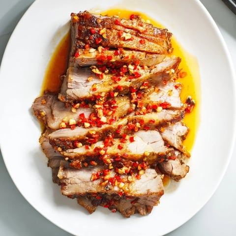 Tender Bavarian roast pork with crispy skin, glistening in chili-ginger sauce, ready to serve.