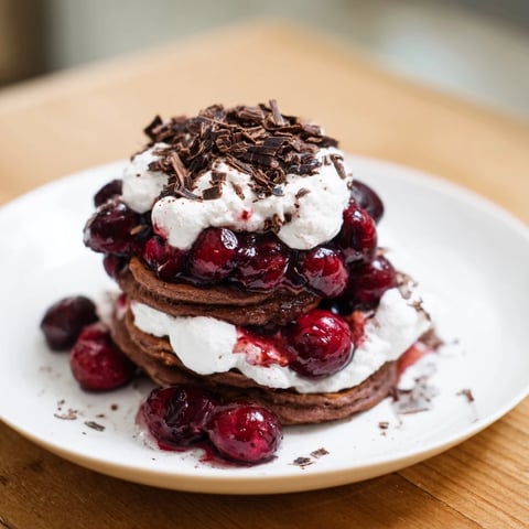 Fluffy Black Forest Pancake Minis drizzled with cherry compote and topped with whipped cream and chocolate.