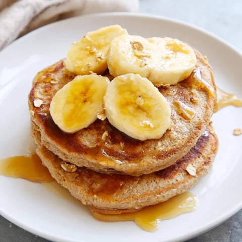 Golden-brown banana oat pancakes drizzled with maple syrup, a perfect easy breakfast.
