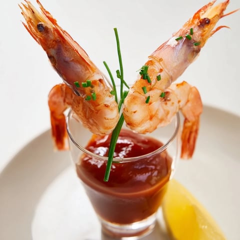 Succulent Retro Prawn Cocktail Shooters, elegantly displayed in shot glasses with vibrant cocktail sauce and prawns.