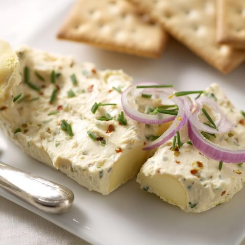 Herzhafter Obazda Käseaufstrich, ideal für Oktoberfest, umgeben von knusprigen Crackern.  