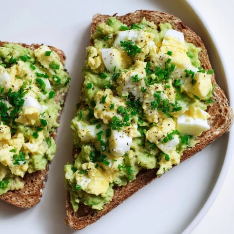 A close-up of avocado egg smash, showing the texture of the mashed avocado and herbs.