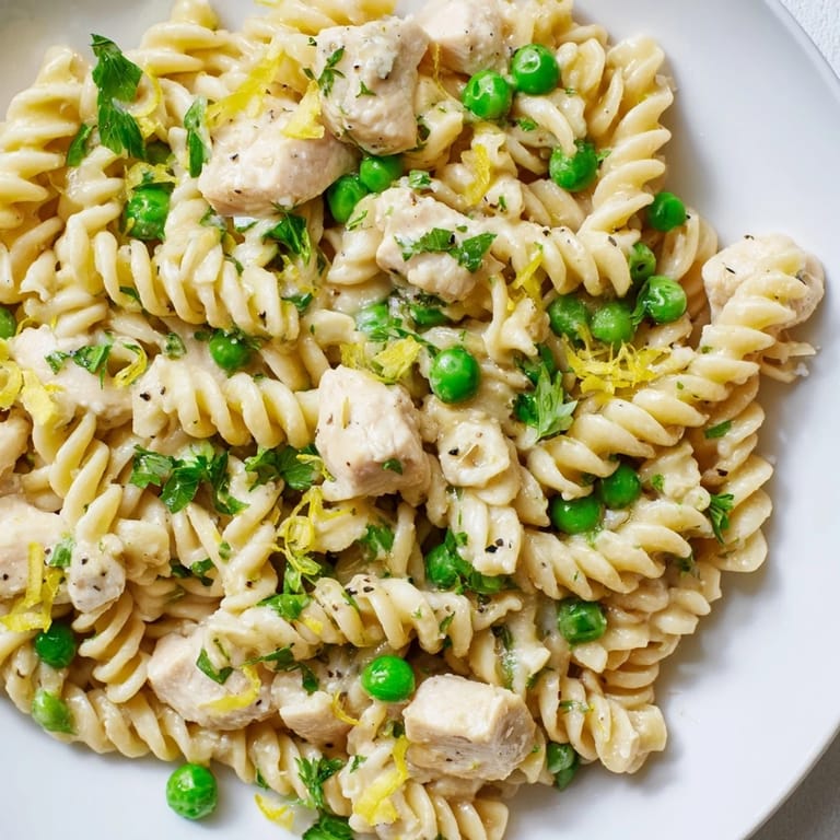 Fork-ready Garlic Butter Chicken & Pea Pasta with bright parsley and lemon zest on a cozy dinner plate.