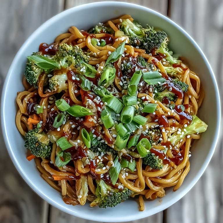 Eine leckere Teriyaki-Nudelschüssel mit weichen Eiernudeln in der glasierten Sauce, frischen grünen Bündelbrokkoli und orangen Karottenstreifen.