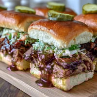 Zarte, rauchige Brisket-Scheiben auf weichen Slider-Brötchen mit würziger BBQ-Sauce und knackigem Krautsalat.